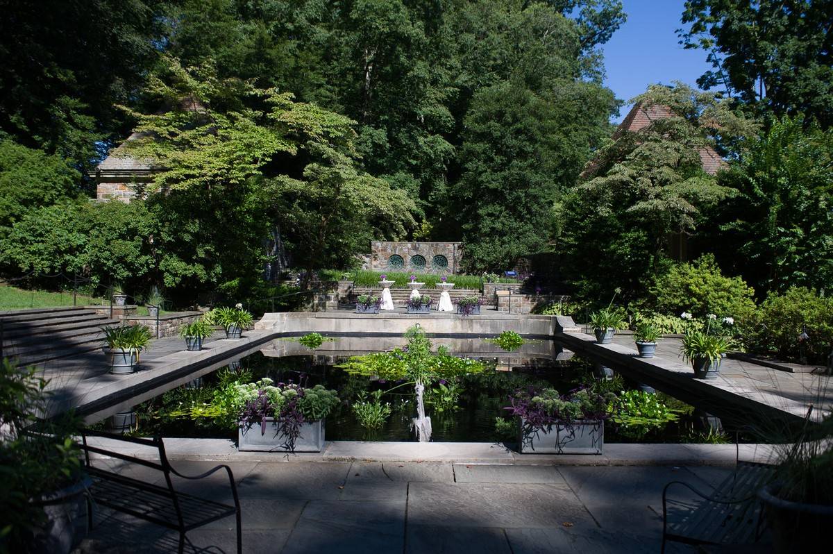 A reflecting pool surrounded by benches and lush greenery.